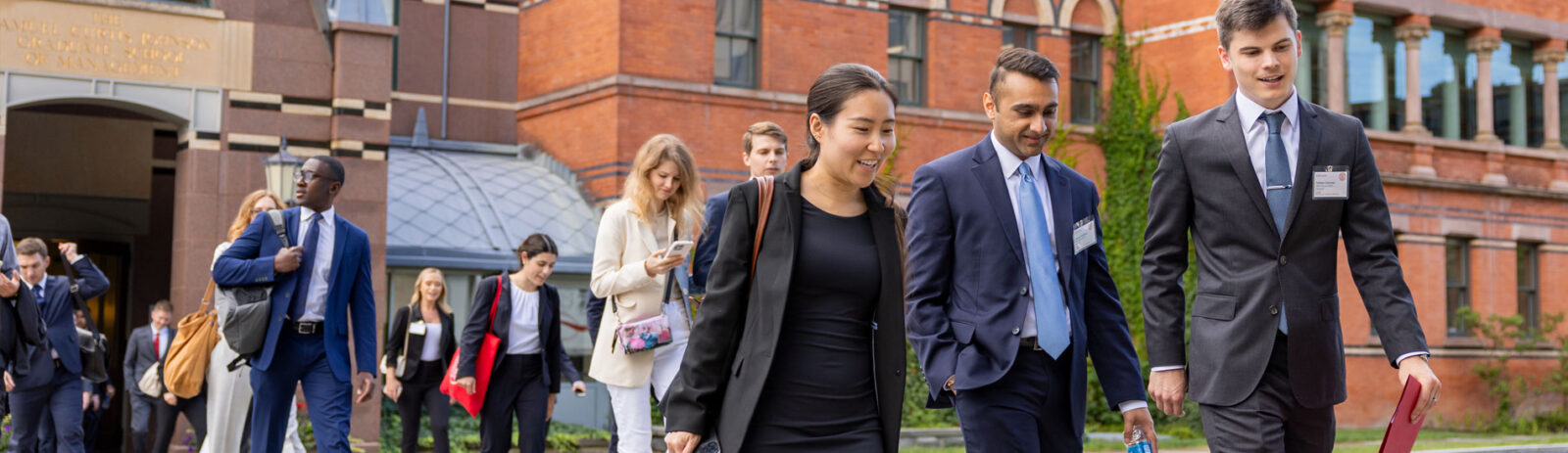 MBA students in business attire walking out of Sage Hall.