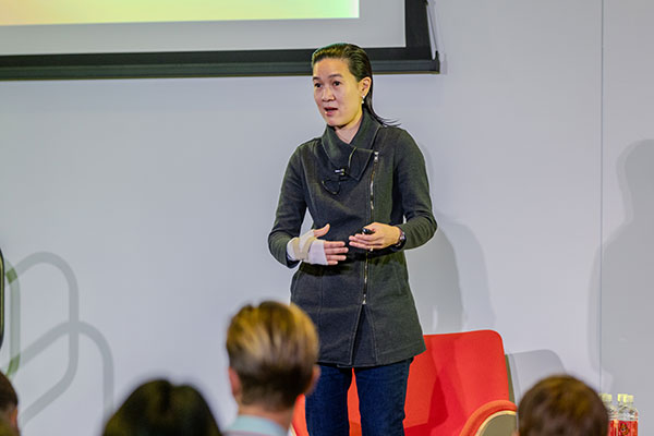 A woman on stage gesturing and speaking.