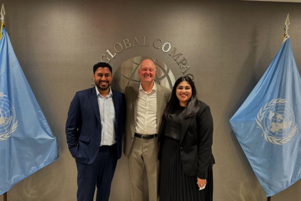 A picture of Archish Mittal, Andrew Karolyi, and unknown in front of the UN logo and flags.