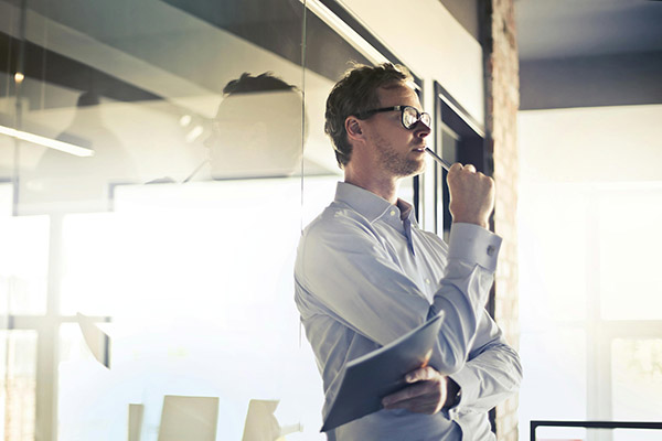 A male professional in an office environment thinking